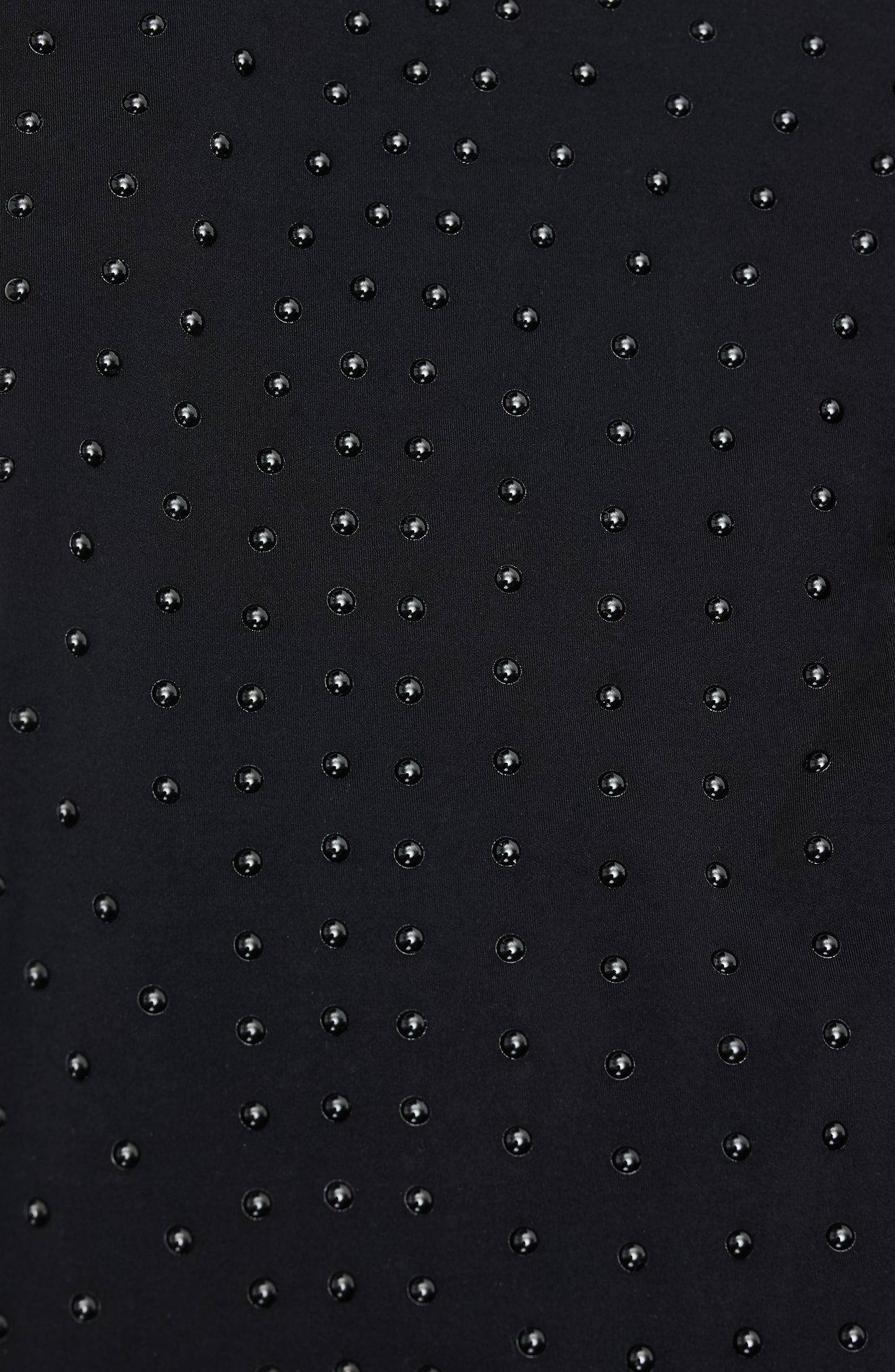 Close-up of Elastique’s MicroPerle® technology on black compression fabric, showing the textured microbeads designed to stimulate lymphatic drainage, improve circulation, and smooth the skin.