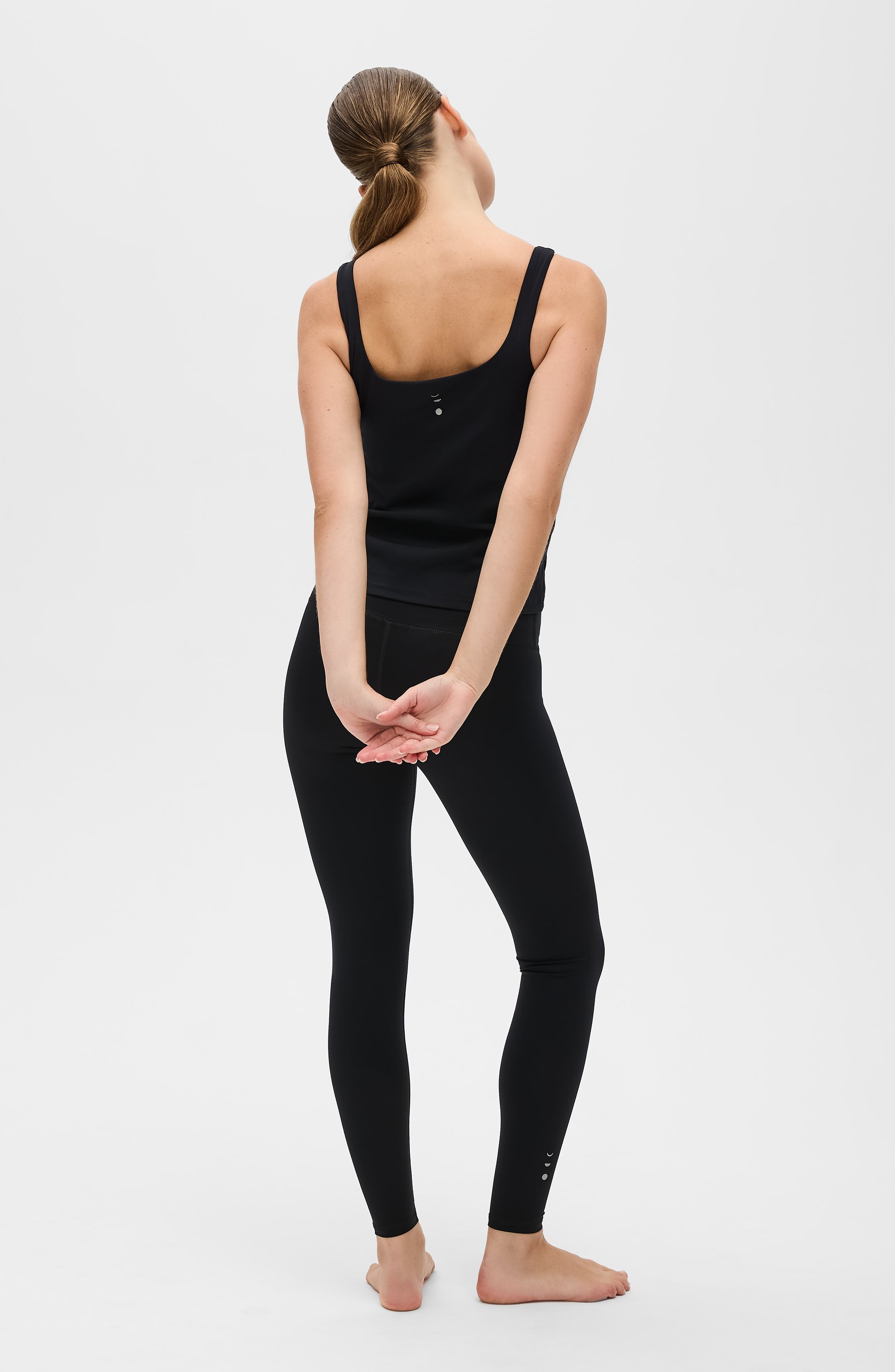 Model wearing the Lisse leggings with matching tank in black, crafted from OEKO-TEX® certified compression fabric designed to sculpt the silhouette, enhance circulation, and deliver a smooth, second-skin feel.