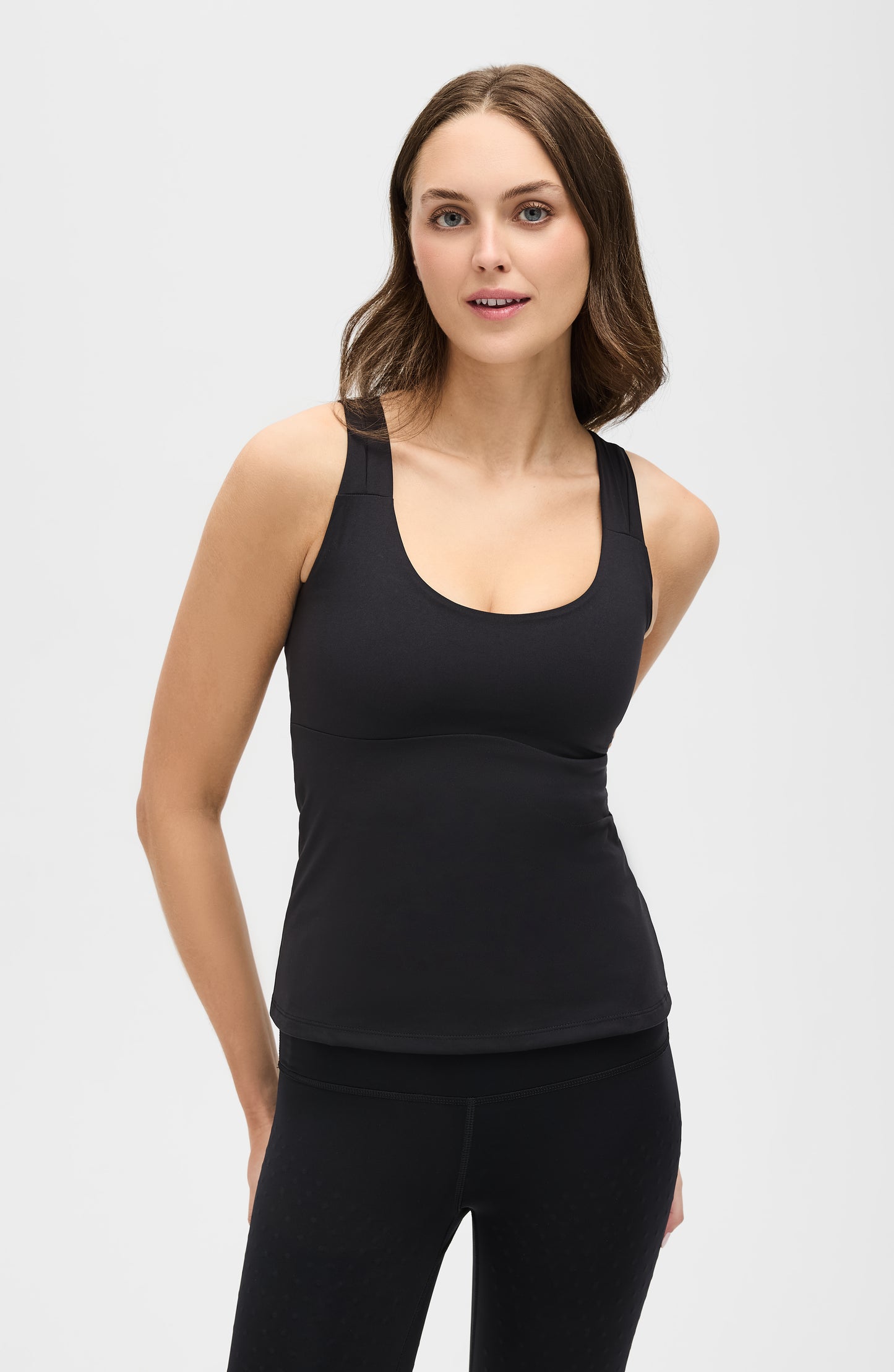 Model wearing the L’Original tank in black, made from OEKO-TEX® certified compression fabric featuring MicroPerle® technology along the back to promote lymphatic drainage, improve circulation, and reduce fatigue.