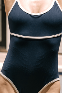 Close-up of the Monte Carlo swimsuit in Navy highlighting the integrated MicroPerle® technology. The textured MicroPerle® pattern is visible across the abdominal area, designed to move with the body and provide a daily lymphatic drainage-inspired massage experience.