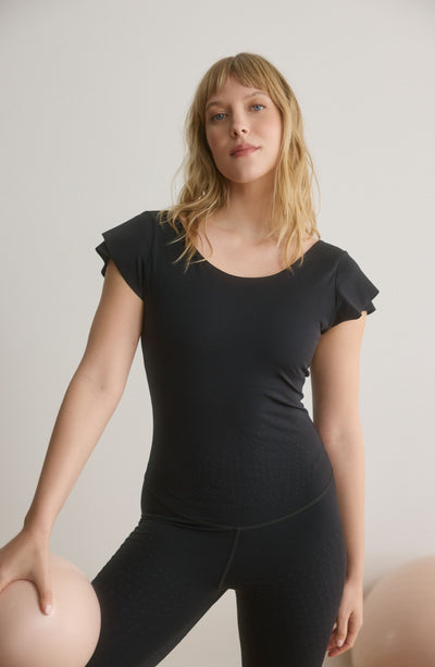 Le Cha-Cha jumpsuit in black featuring a sophisticated open back, delicate sleeve detailing, and a sleek, sculpting silhouette. Crafted from OEKO-TEX® certified compression fabric with Elastique’s MicroPerle® technology to promote lymphatic drainage, boost circulation, reduce fatigue, and enhance vitality.