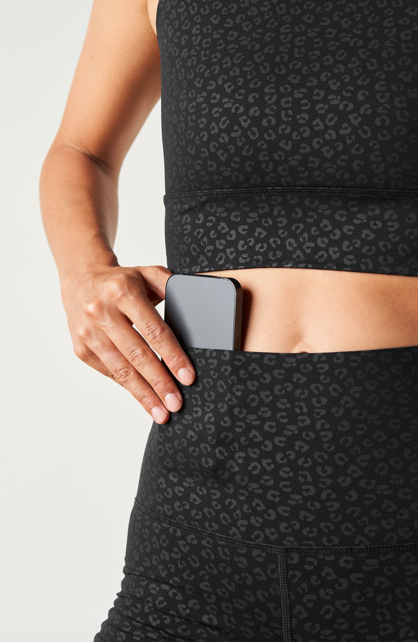 Model wearing The Fierce leggings and bra in black with cheetah print, made from OEKO-TEX® certified compression fabric featuring Elastique’s MicroPerle® technology to enhance lymphatic drainage, improve circulation, reduce fatigue, and smooth the skin.