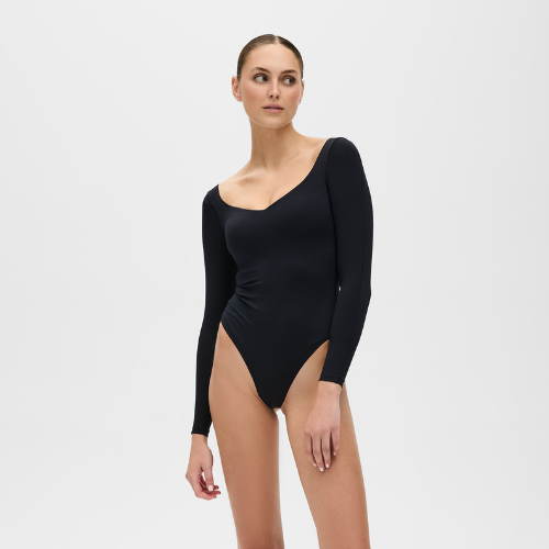 Woman wearing a black long-sleeve bodysuit on a light gray background
