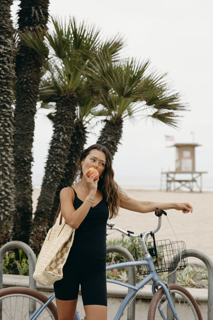 Model wearing the black Iconic Tank in a sculpting, compressive fit with an elevated neckline and built-in bra. Designed with MicroPerle® beads along the back panel for lymphatic stimulation and posture support, this sleek tank transitions effortlessly from activewear to refined layering piece.