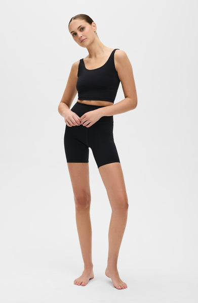 Model wearing the Lisse bike short with matching bra in black, made from OEKO-TEX® certified compression fabric designed to smooth, sculpt, and support the body for optimal comfort and circulation.