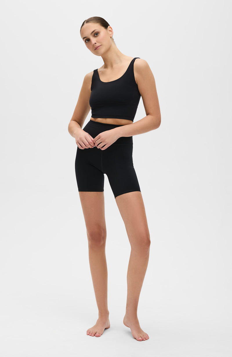 Model wearing the Lisse bike short with matching bra in black, made from OEKO-TEX® certified compression fabric designed to smooth, sculpt, and support the body for optimal comfort and circulation.