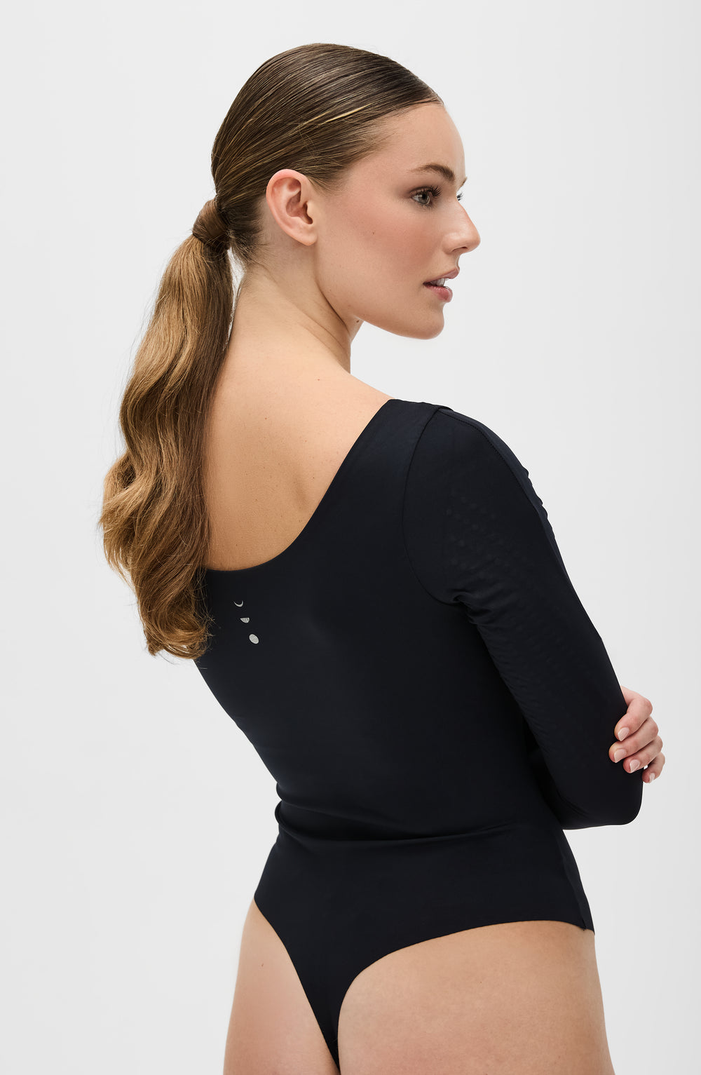The Iconic Lymphatic Long Sleeve Bodysuit - Thong with MicroPerle in black. Designed to enhance circulation, provide gentle compression, and sculpt effortlessly with OEKO-tex certified compression fabric, our MicroPerle® technology placed on the arms for lymphatic drainage, better circulation, reducing fatigue