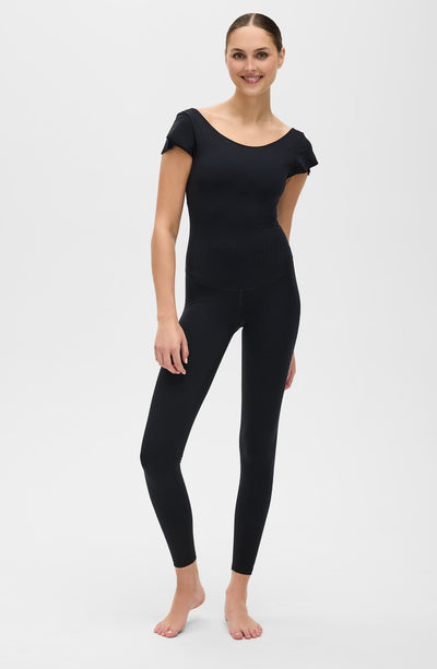 Le Cha-Cha jumpsuit in black featuring a sophisticated open back, delicate sleeve detailing, and a sleek, sculpting silhouette. Crafted from OEKO-TEX® certified compression fabric with Elastique’s MicroPerle® technology to promote lymphatic drainage, boost circulation, reduce fatigue, and enhance vitality.