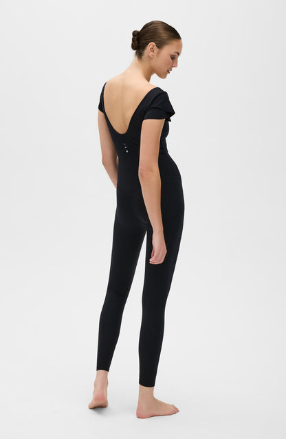 Le Cha-Cha jumpsuit in black featuring a sophisticated open back, delicate sleeve detailing, and a sleek, sculpting silhouette. Crafted from OEKO-TEX® certified compression fabric with Elastique’s MicroPerle® technology to promote lymphatic drainage, boost circulation, reduce fatigue, and enhance vitality.