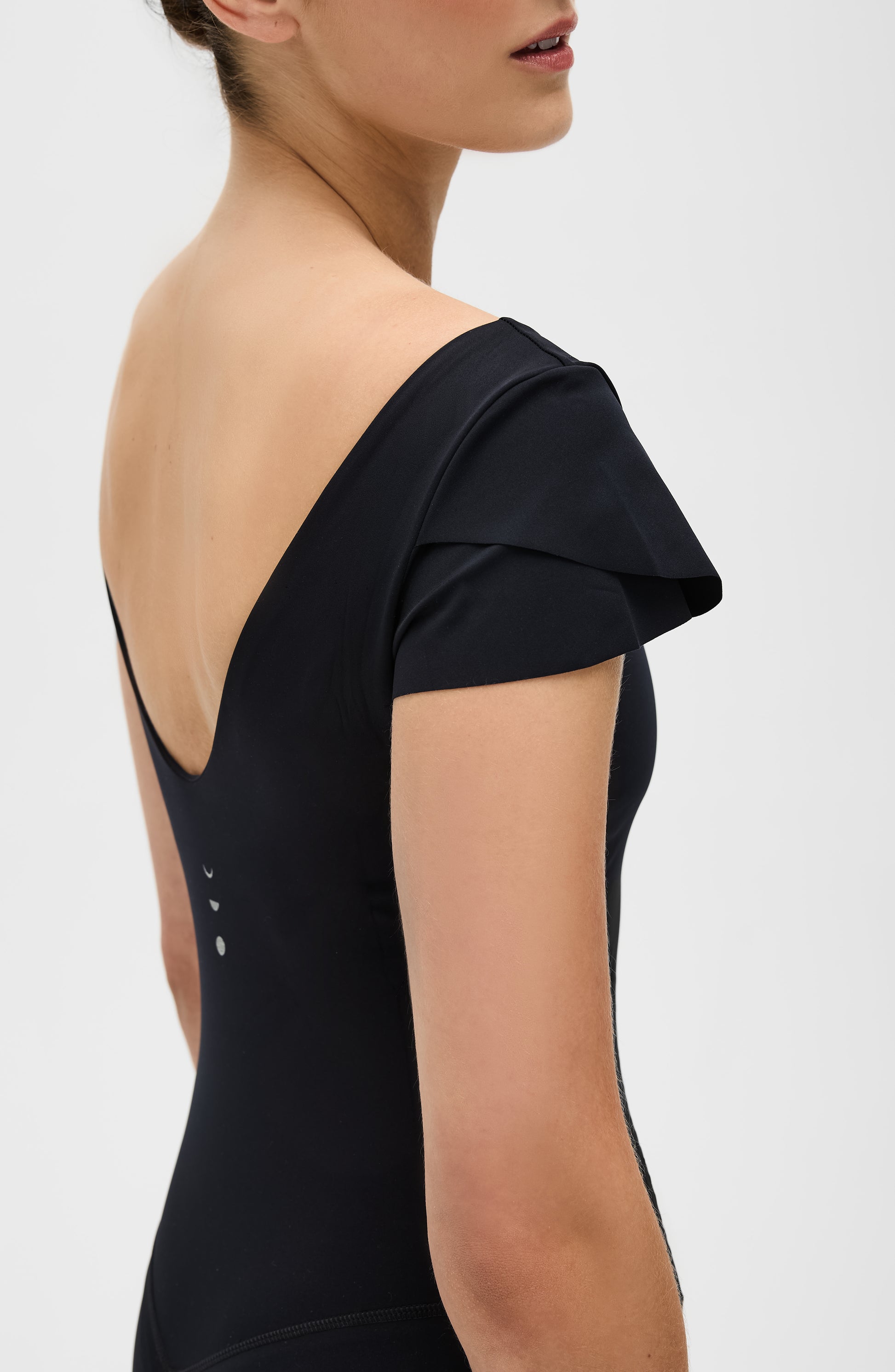 Le Cha-Cha jumpsuit in black featuring a sophisticated open back, delicate sleeve detailing, and a sleek, sculpting silhouette. Crafted from OEKO-TEX® certified compression fabric with Elastique’s MicroPerle® technology to promote lymphatic drainage, boost circulation, reduce fatigue, and enhance vitality.
