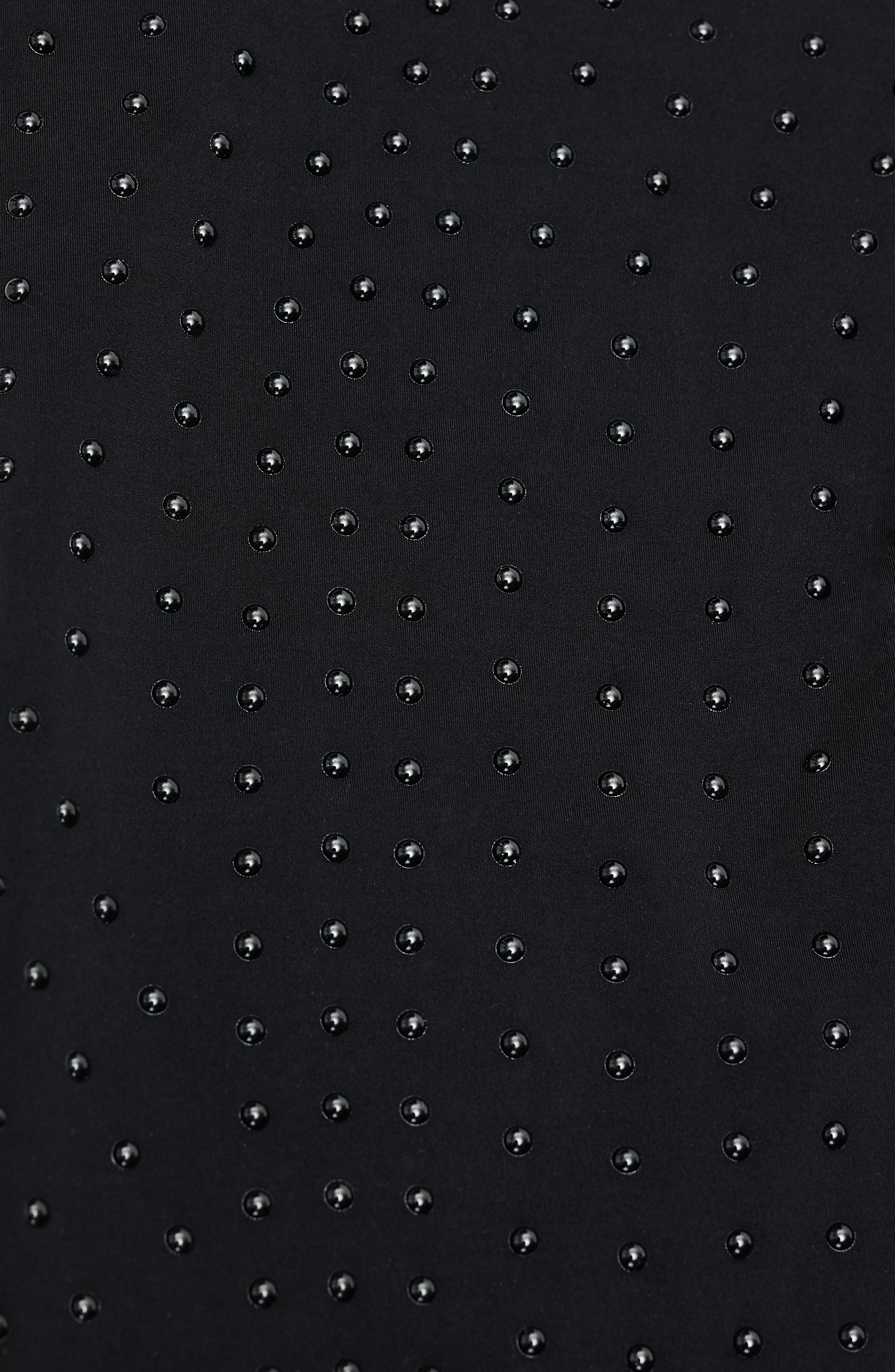 Close-up of Elastique’s MicroPerle® technology on black compression fabric, showing the textured microbeads designed to stimulate lymphatic drainage, improve circulation, and smooth the skin.