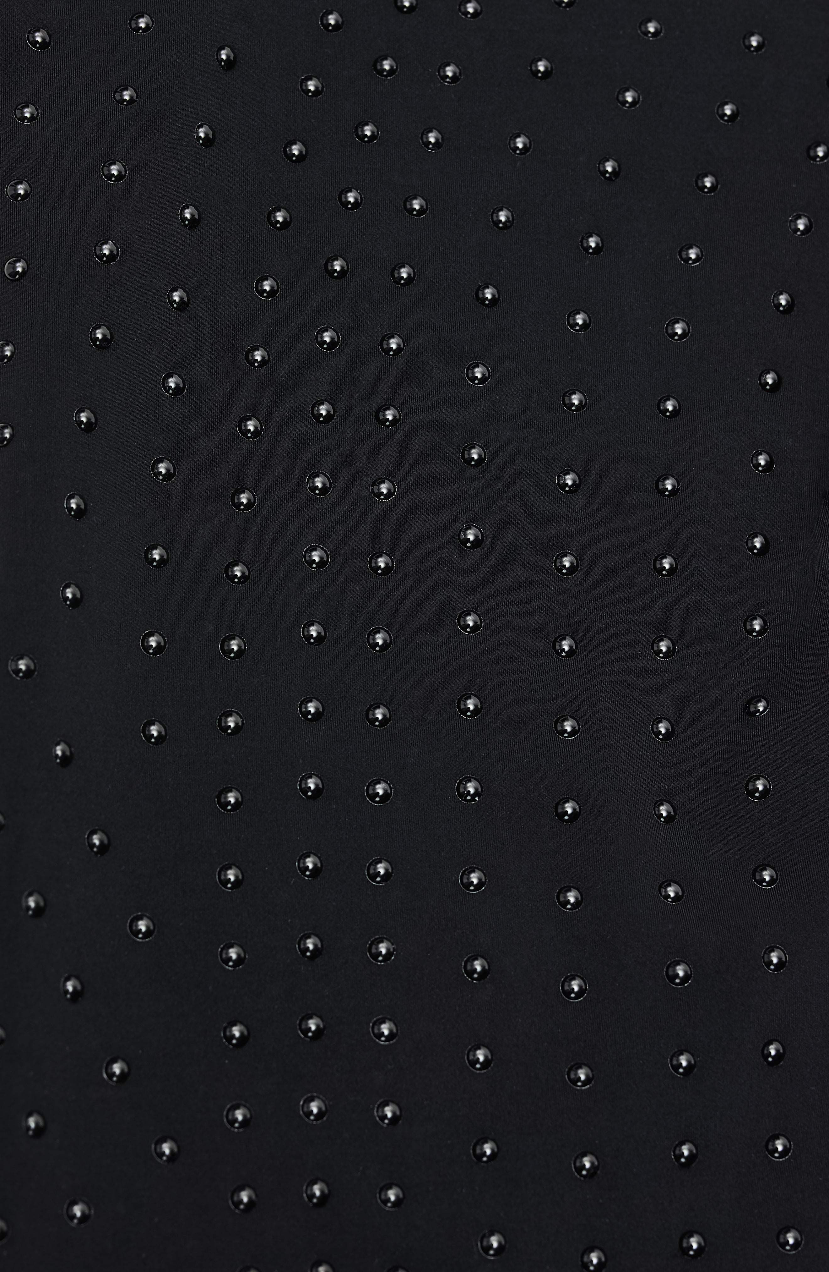 Close-up of Elastique’s MicroPerle® technology on black compression fabric, showing the textured microbeads designed to stimulate lymphatic drainage, improve circulation, and smooth the skin.