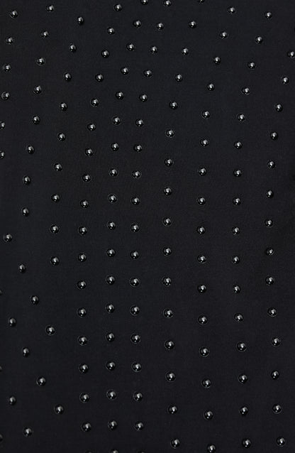 Close-up of Elastique’s MicroPerle® technology on black compression fabric, showing the textured microbeads designed to stimulate lymphatic drainage, improve circulation, and smooth the skin.