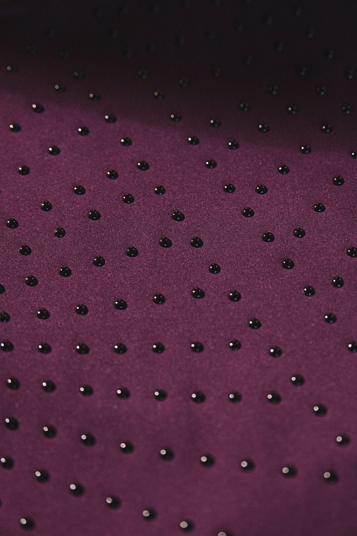 Close-up of Elastique’s MicroPerle® technology in fig color compression fabric, showing the textured microbeads designed to stimulate lymphatic drainage, improve circulation, and smooth the skin.