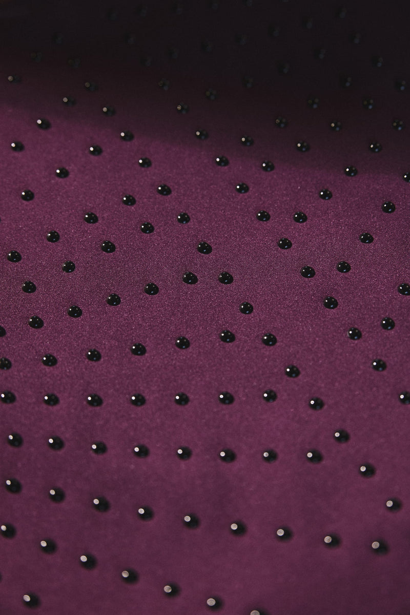 Close-up of Elastique’s MicroPerle® technology in fig color compression fabric, showing the textured microbeads designed to stimulate lymphatic drainage, improve circulation, and smooth the skin.