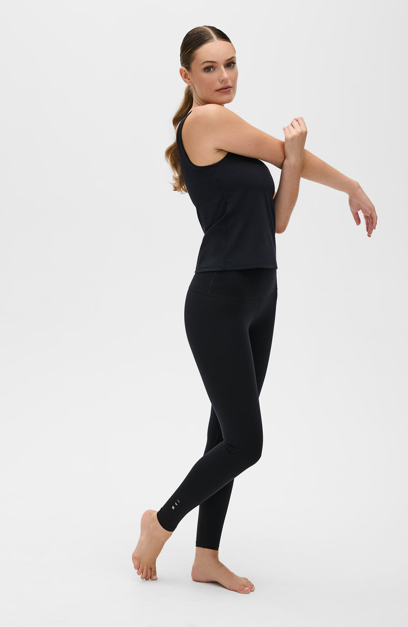 Model wearing the Lisse leggings with matching tank in black, crafted from OEKO-TEX® certified compression fabric designed to sculpt the silhouette, enhance circulation, and deliver a smooth, second-skin feel.