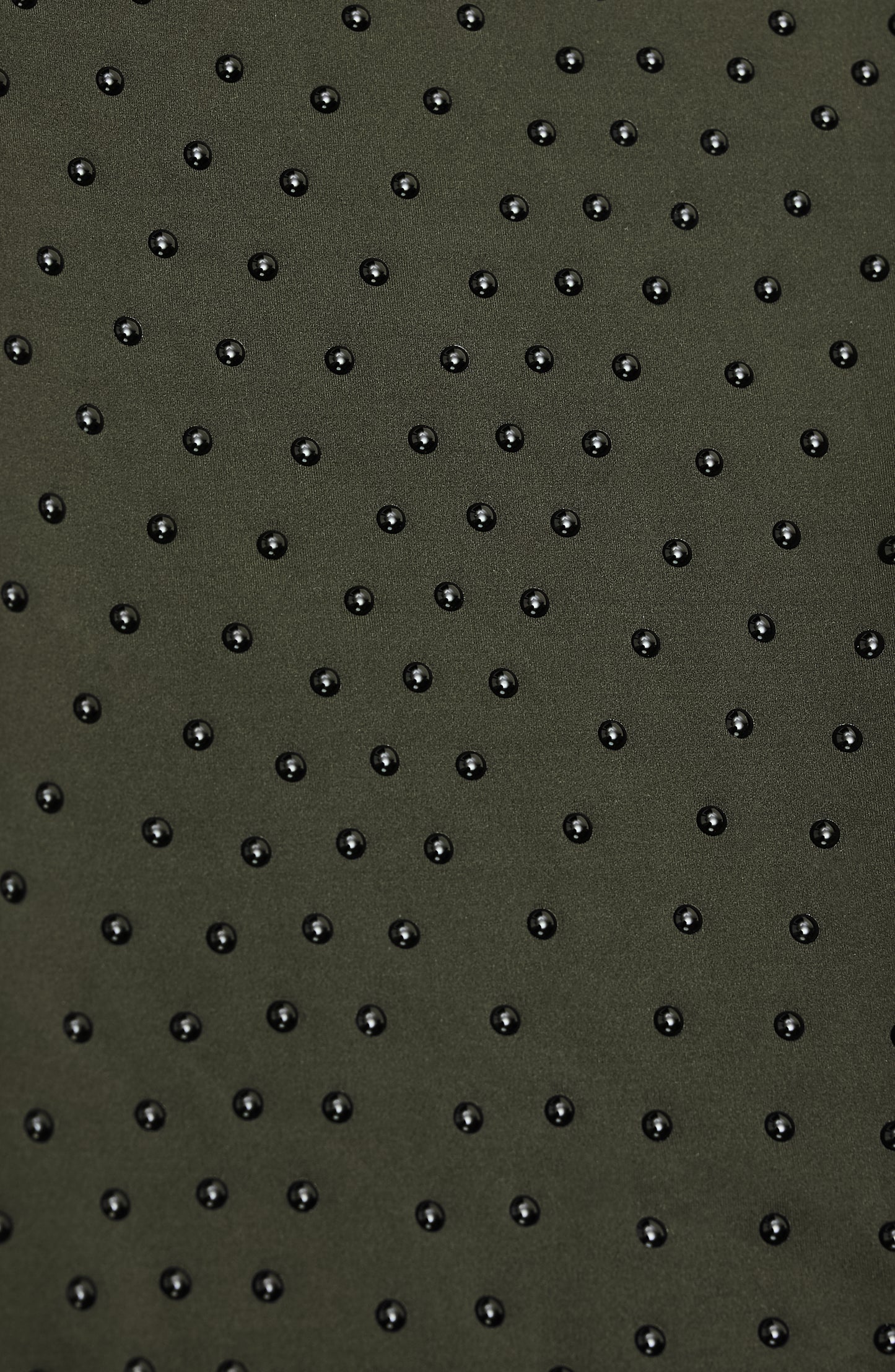 Close-up of Elastique’s MicroPerle® technology in olive green compression fabric, showing the textured microbeads designed to stimulate lymphatic drainage, improve circulation, and smooth the skin.
