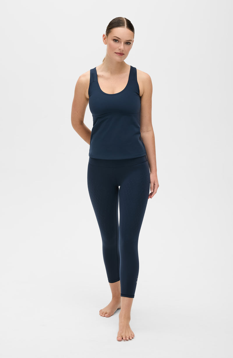 Model wearing the L’Original leggings and tank in navy blue, made from OEKO-TEX® certified compression fabric featuring MicroPerle® technology along the back to promote lymphatic drainage, improve circulation, and reduce fatigue.