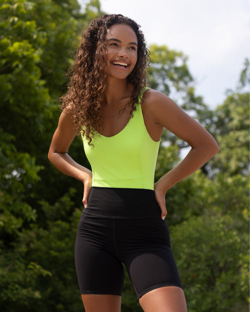 Load image 1 in gallery view. Model wearing Riviera Bodysuit in Lime Green color with black bike short