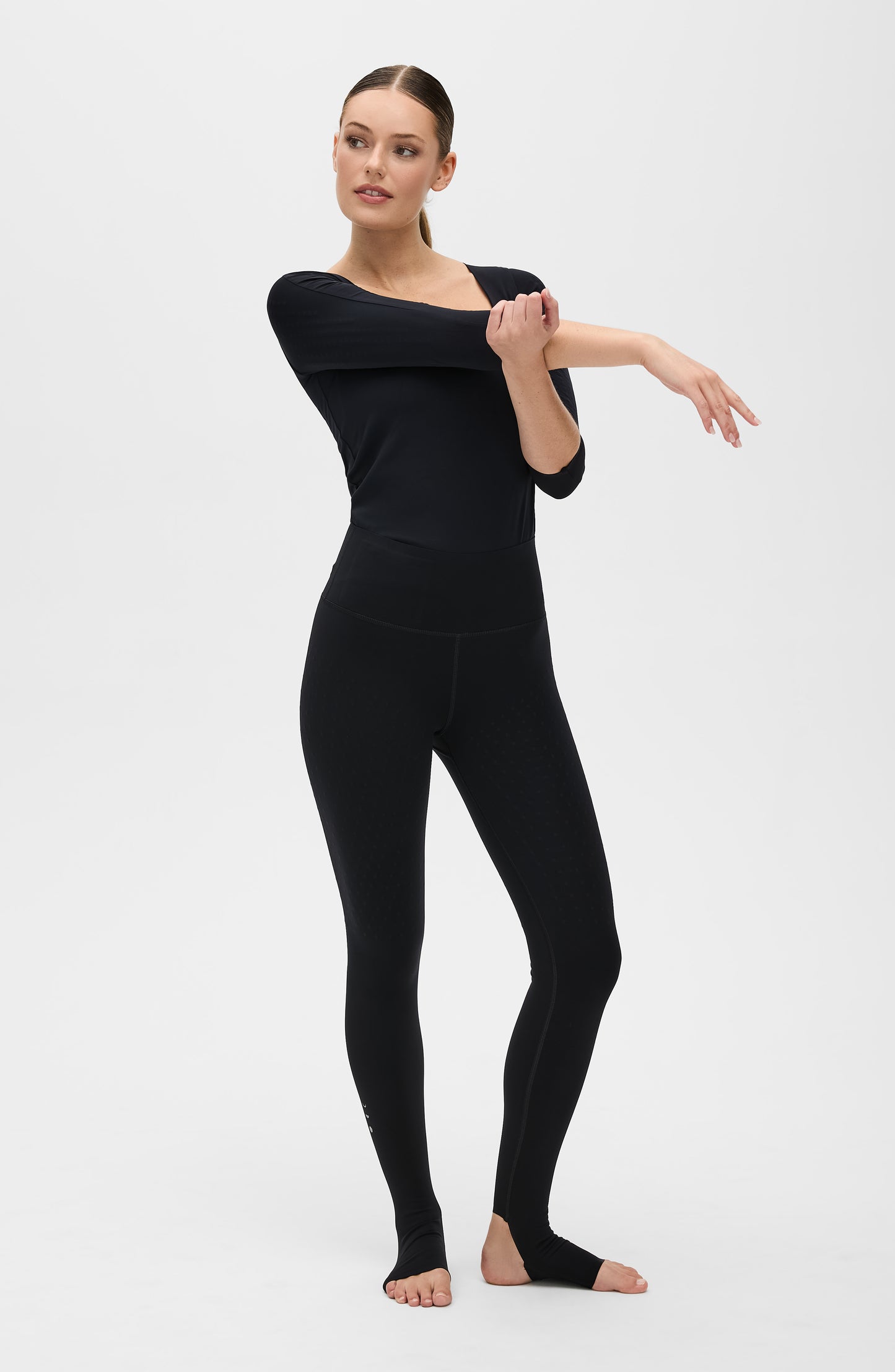 Model wearing L’Original stirrup leggings in black with Iconic 3/4 sleeve MicroPerle top featuring Elastique’s MicroPerle® technology on OEKO-TEX® certified compression fabric to enhance circulation, support lymphatic drainage, and provide pain relief.